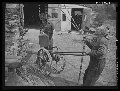 Dr. Bair, college professor and inventor, saws steel billits to swell the volume for victory. He and his son use a homemade cart to wheel billets to power saws