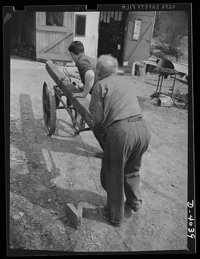 Dr. Bair, college professor and inventor, saws steel billets to swell the volume for victory. He and his son use a homemade cart to wheel billets to power saws
