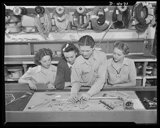 Women aircraft workers. Precision assembly at a West Coast aircraft factory. A leadman explains the use of wiring jigs in making up assembly to three of the plant's attractive young war workers. Lockhead