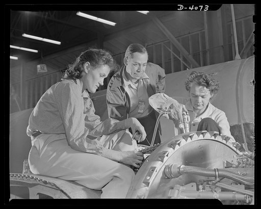 Women aircraft workers. Perched high on the wing of a giant bomber, women of a large West Coast aircraft factory are speeding the installation of electrical units contolling the engine. The leadman, center, goes from team to team, checking work, lending advice and assistance when necessary. Women ar