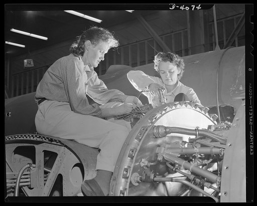 Women aircraft workers. Perched high on the wing of a giant bomber, women of a large West Coast aircraft factory are speeding the installation of electrical units controlling the engine. In this, as in many other U.S. plants, women are gradually replacing or augmenting men on assembly lines, doing i