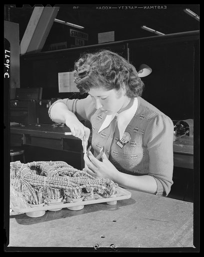 Women aircraft workers. An attractive brunette performs a job vital to Uncle Sam's victory push. She's one of the hundreds of women employed by a West Coast aircraft plant, pictured at work on a complex electrical assembly. Vega