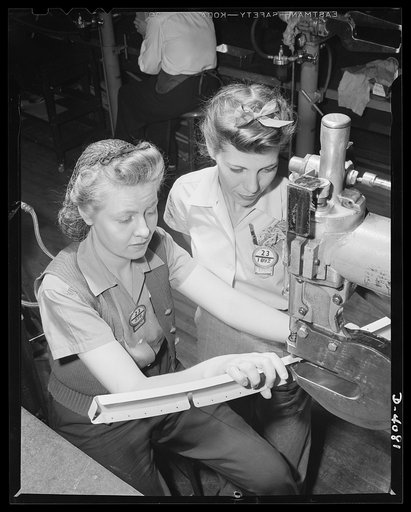 Women aircraft workers. An experienced girl worker in a West Coast airplane factory trains a new girl in the use of a rivet-squeezing machine. Vega