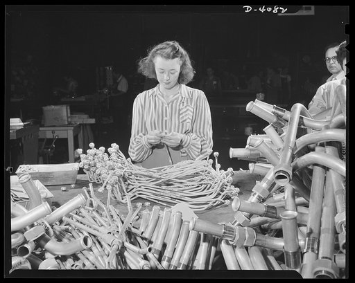 Women aircraft workers. One of the hundreds of young women employed in a West Coast aircraft factory applies identifying marking tape to plumbing sub-assemblies. Vega