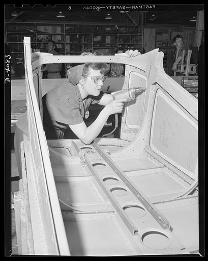 Women aircraft workers. She can't forget Pearl Harbor, and she's determined that Hitler and Hirohito shall have cause to remember it. Mrs. Evelyn J. W. Casola, Pearl Harbor widow, drills rivet holes in the belly gun door of a U.S. bomber, soon to storm over Axis lands, showing death to the aggressor