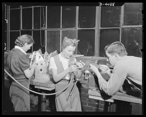 Women aircraft workers. Men and women work together training planes for Uncle Sam's fighing flyers at a West Coast plant. Here, Mrs. Fern Evans, Pearl Harbor widow, works on a radio bracket for a bomber with a young mechanic. Mrs. Evans, who had no previous mechanical experience when she applied for
