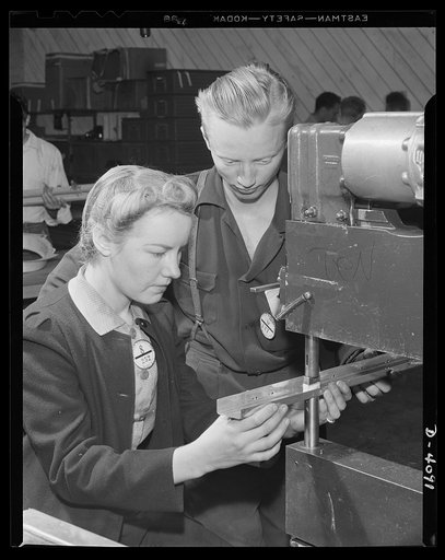 Women aircraft workers. Looks like "boy meets girl" in wartime and in war plants, but it's serious business here, for these two are among the hundreds of young people employed in a West Coast aircraft plant. He's a leadman and is instructing her in the use of a power rivet-squeezing machine