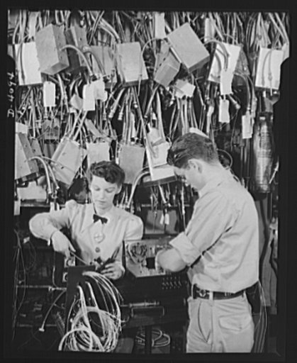 Women aircraft workers. Men and women work together at one of the West Coast's huge aircraft plants. These two are working on an electrical control panel