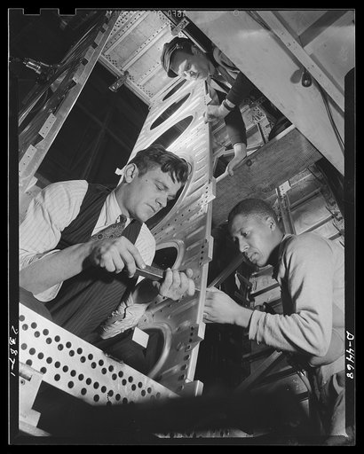 Production. Bombers. High speed bomber production at new plant. Advanced manufacturing methods ensure record output. Fixtures are used in places instead of jigs. Frame section is riveted by the man at the right, while the man at the left bucks up the rivets