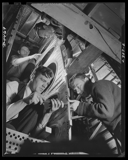 Production. Bombers. High speed bomber production at new plant. Advanced manufacturing methods ensure record output. Fixtures are used in places instead of jigs. Frame section is riveted by the man at the right, while the man at the left bucks up the rivets