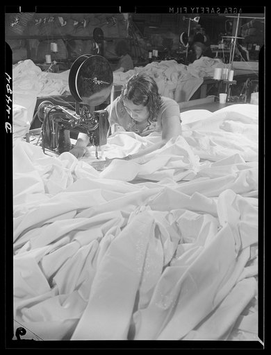 Manpower. Negro navy yard workers. In a sea of silk, this woman worker is making parachutes for America's paratroopers. She is one of many Negro employees in the aircraft factory of an Eastern navy yard