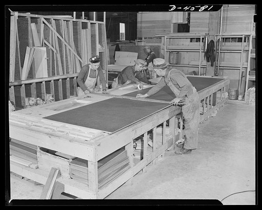 Production. War housing trailers. The side of a war housing trailer nears completion on a table-top jig at Western Trailer Company's plant in Los Angeles. Exceptional strength is secured through built-up construction of Masonite over plywood with a casein bond. The side is secured to spacers with dr