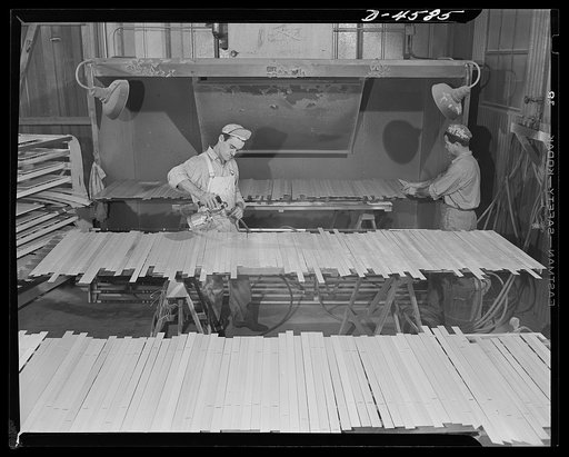 Production. War housing trailers. Trailers for war housing are built by mass production methods at the Los Angeles plant of the Western Trailer Company. Workmen use spray guns to apply clear lacquer to hundreds of small parts before installation. The power exhaust in the background reduces fire and 