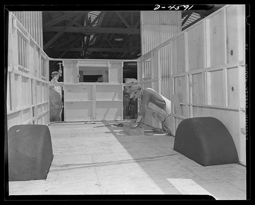 Production. War housing trailers. The front end section of a war housing trailer goes into place at the Los Angeles plant of Western Trailer Company. Plastic wheel wells, which will shortly be covered by cabinet work, are made of paper impregnated with a special hardening solution and formed over mo