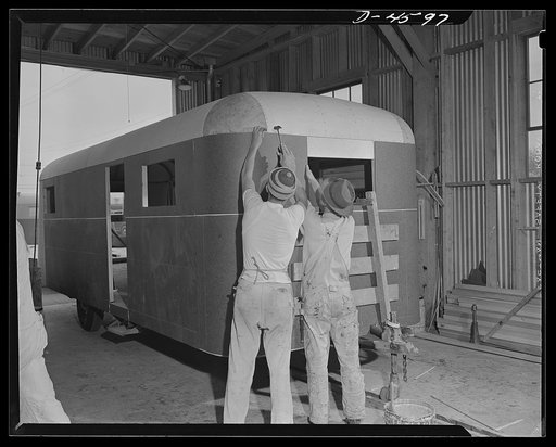 Production. War housing trailers. Small corner sections are installed on a war housing trailer nearing completion in the Los Angeles plant of Western Trailer Company. Clamps hold big pieces of Masonite in place while the glue dries