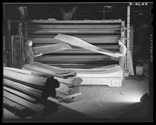 Production. Veneer for aircraft and other war essentials. A strip of walnut veneer that will be used in a panel of a combat plane comes from the textile dryer of a Midwest plant. This operation reduces the moisture content to about eight to ten percent. Sheets are stacked in exact sequence just as t