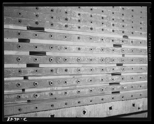 Production. Plywood for aircraft and boats. Making plywood panels for combat planes and boats. A huge hydraulic press operating at high temperature and a pressure of 250 pounds per square inch attaches glue-surfaced veneer sheets to lumber-core panels to make high-grade plywood for Army and Navy use