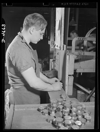 Conversion. Duck decoys to incendiary bomb noses. Polishing incendiary bomb noses on an emery belt that the same worker was using a short time ago to sand duck decoys for American sportsmen. A broad conversion in which a woodworker and woodworking machinery changed over to metal working