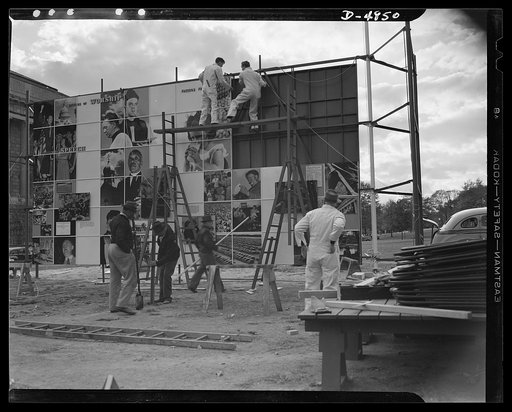 Four Freedoms and Arsenal of Democracy posters. Assembly workers are nearly ready to put the final section of the huge 15 x 30 foot photmontage The Four Freedoms in place. On the other side of the scaffolding was the Arsenal of Democracy panel, equal in size. The two were displayed in Defense Square
