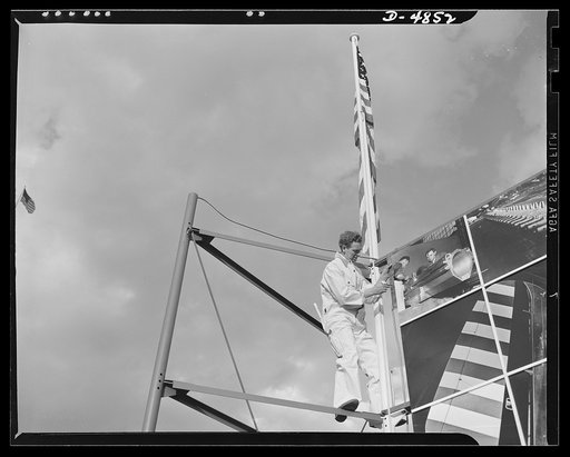 Four Freedoms and Arsenal of Democracy posters. This worker is completing the border on the 15 x 30 foot Arsenal of Democracy photomontage. On the other side of the scaffolding was the Four Freedoms panel, equal in size. The two were displayed in Defense Square, Washington beginning November 7, 1941
