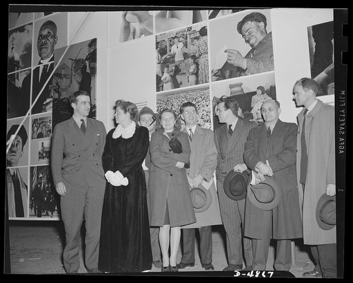 "Open the doors," says Jean Carlu, eminent poster artist, to Manager Sloan of the National and Civilian Defense Exposition at New York's Grand Central Palace. In the background is part of the 15 x 30 foot poster Carlu designed for the Office of Emergency Management (OEM). The panel shown represents 