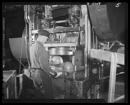 Conversion. Auto radiators to army helmets. Heavy presses trim the edges of army helmets that have been formed on drawing presses. All these presses, which were stamping out auto radiator parts a short time ago, were retooled for conversion to war work. McCool Radiator Company, Detroit, Michigan
