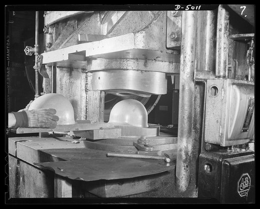 Conversion. Auto radiators to army helmets. "Spanking," or forming  the edge of a steel army helmet. This operation, performed on a medium-sized press in a converted auto radiator plant, is part of the process of making helmets from flat sheets of steel. McCool Radiator Company, Detroit, Michigan