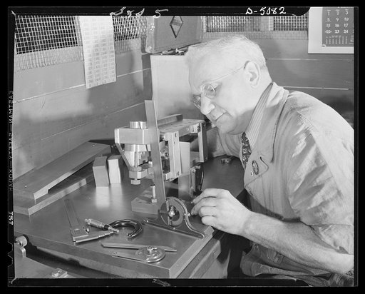 Conversion. Paper machinery to plant wing parts. A toolmaker in the plant of an Eastern paper machinery manufacturer inspects and tests drill jig fixtures for wing hinge fitting. Naval sights and other war essentials are also made in this plant