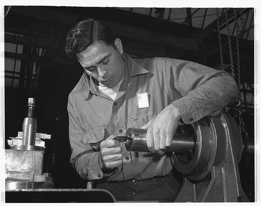 Conversion. Automobiles to 40 mm. anti-aircraft guns. To ensure maximum efficiency, every 40 mm. anti-aircraft gun barrel made in this former automobile plant is checked and double checked. Here an inspector is examining the size of the bore in an army barrel. Chrysler Corporation, Highland Park, De