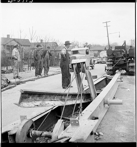 Buried trolley tracks salvaged to aid war program. Removing abandoned trolley tracks to provide much needed scrap for Uncle Sam. Here, in Asheville, North Carolina, a local inventor demonstrates his "railjerk" for doing the trick. He claims his device, employing three men, can pry loose a mile of tr