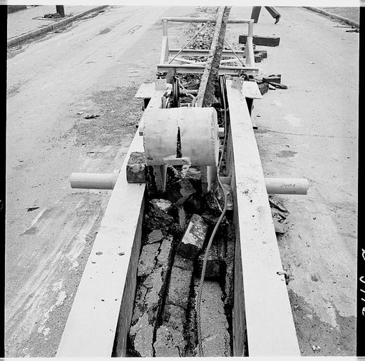 Buried trolley tracks salvaged to aid war program. Recovering buried trolley track to provide scrap for the war effort is an operation handily performed by such devices as the one shown here. Pulled by a tractor, the apparatus disengages the track from the pavement and slides it back on the iron saw