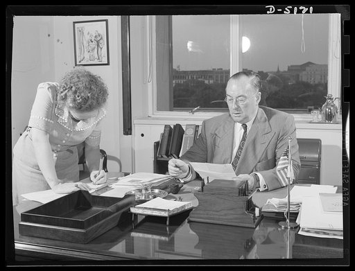 America's production chief. Arriving at his office about 8:30, Donald Nelson, Chairman of the War Production Board (WPB), tackles a stack of correspondence with his secretary, Miss Iona Thornton, before plunging into the daily conferences. He has no rigid iroutine for work since each day is shaped b