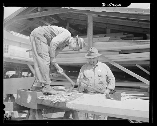 Production. Minesweepers. House carpenters turn shipbuilders - and do a good job of it. The man shaping the stem of a new minesweeper's box with an adze has become proficient at an ancient but still indispensible art. Location: an Eastern shipyard. Gibbs Cass Company