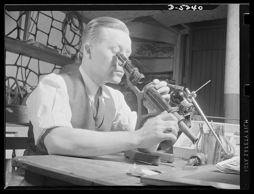 Subcontracting. Passaic home workshop pool. Jack Vida, of Passaic, New Jersey, inspects precision lenses he ground for military use in his home workshop. In addition to this work, Mr. Vida employs four men to turn out machine tools for aircraft production as a member of a subcontract pool organized 