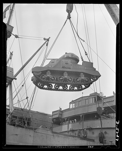 How lend-lease strikes at the Axis. A lend-lease tank coming over the side of a cargo ship in a United States Atlantic Coast port. Many tanks are carried as deck-load