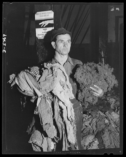 Salvage. Wool reclamation. A workman in an Eastern plant, reclaiming wool from old rags, holds on his right arm a collection of rags before they have passed through the rag-picking machine. On his left arm is wool fiber after being shredded from wool rags in a rag-picking machine