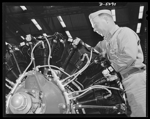 Production. Aircraft. A master mechanic works over a Flying Fortress power plant at a big Western aircraft factory