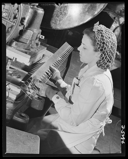 Production. Aircraft. A young woman worker operates a heavy punch-press in a large Western aircraft plant. A new hair net keeps her hair out of harm's way; gloves protect her hands from metal splinters