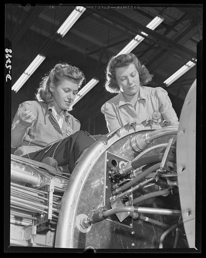 Production. Aircraft. High on the wing of a Vega Ventura bomber, these girl electricians complete a complicated wiring assembly
