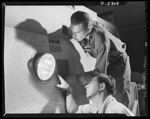 Production. Aircraft. Aircraft mechanics check the installation of a 50,000 candle-power landing light in the wing of a YP-38 plane under construction in a large Western plant