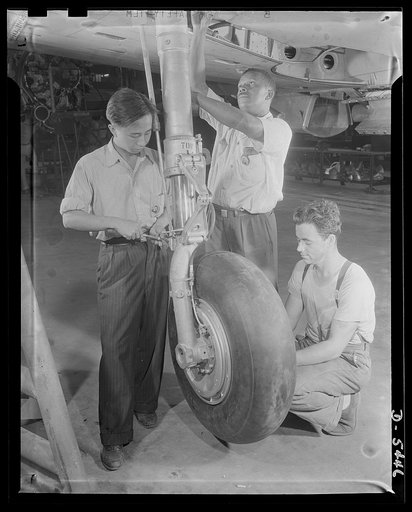 Americans all. At an Eastern aircraft factory, Philip Leung, Chinese; Marcell Webb, Negro; and an unidentified white worker adjust the retractable landing gear of a pursuit plane on the final assembly line. Republic Aircraft Corporation