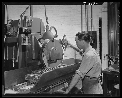 Production. Airplanes. Machinist at work on a main-beam wing joint of a YP-38 plane in production at a big Western plant. The machine is a Gallmeyer-Livingston surface grinder
