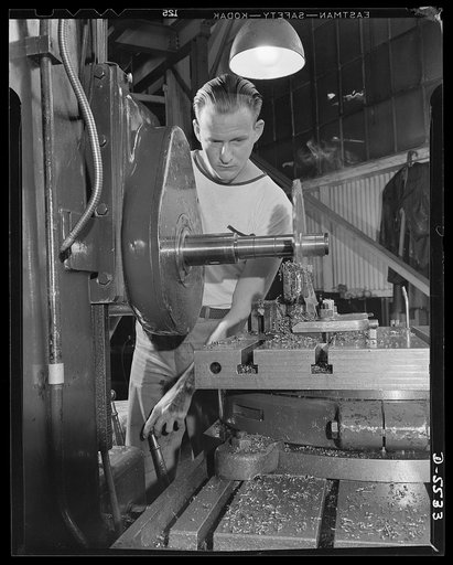 Production. Airplanes. A machinist's apprentice on a Universal boring machine in a big Western airplane plant. Cutting a part for a manufacturing jig with a twelve inch milling cutter