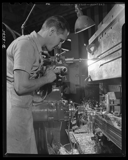 Production. Airplanes. A toolmaker's apprentice at work on a Pratt and Whitney automatic tool room machine in a large Western aircraft plant. He is working on a flap track for a Lockheed Model 58