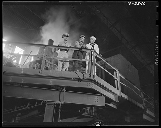 A poster comes to life. On the bridge of the "S.S. Production," the three men standing on the electric-furnace floor, watching the men below pour molten metal from the furnace into ingot molds. Removed though they were from the pouring operation, the heat rising towards them was still intense. Alleg