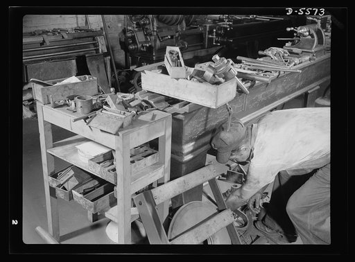 Industrial safety. Accident prevention. A cluttered work bench is hazardous. This worker could be seriously injured by thoughtlessly raising his head a trifle. In addition, the disorder creates a hazard in the aisles