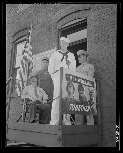 A poster comes to life. "I know now where we get the stuff for battleships and guns--and even radio parts. And with men like you producing this stuff we need and backing us up, we can't lose this war." Chief Evans speaks to the steelworkers on his visit to an Allegheny-Ludlum mill. Touring the plant