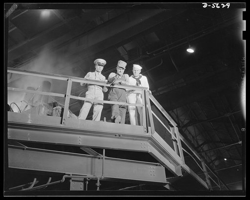 A poster comes to life. On the bridge of the "SS Production" at Allegheny-Ludlum, Sergeant Vineyard, welder George Woolslayer and Aviation-radio Chief John Evans watch the ceaseless chain of ladles brimming with molten steel on the furnace floor below. Chief Evans has been in the Navy for twelve lon