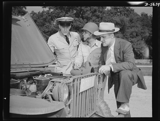 A poster comes to life. "Never got so close to one of these babies before" says George Woolslayer (right) giving an army jeep the once-over. At the post where Sergeant French L. Vineyard (center) is stationed, Woolslayer learned a great many things about army operations. Aviation-radio Chief John Ma