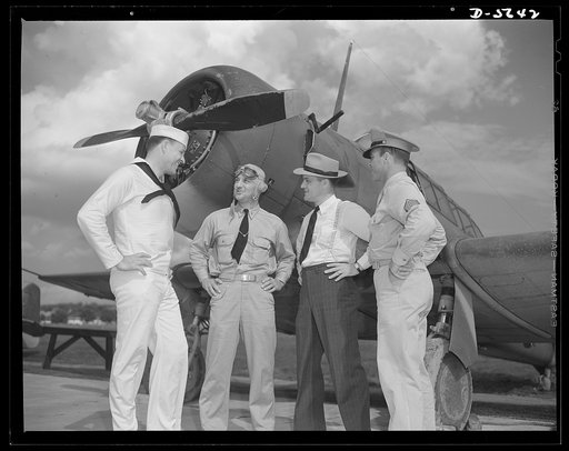 A poster comes to life. A couple of groundhogs get a liberal education from a Navy pilot as Aviation-radio Chief John Marshall Evans (left) escorts welder George Woolslayer and Sergeant French L. Vineyard (right) through his navy post. The three colleagues of the "Men Working Together" poster learne